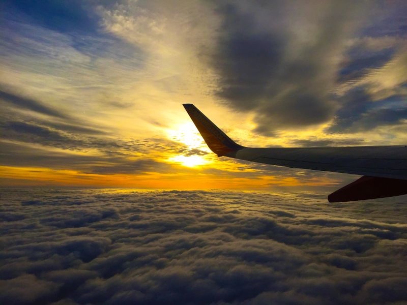 Sayap pesawat di atas awan saat matahari terbenam