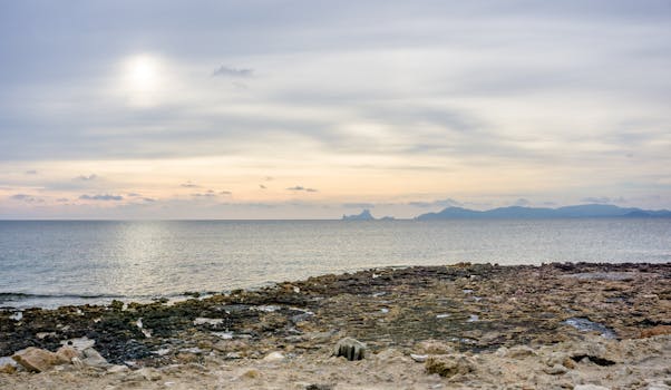 Serene sunset over rocky seashore in Ibiza, Spain, capturing peaceful coastal beauty.