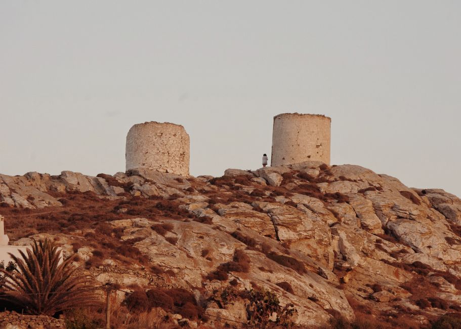 Two ancient windmills on a rocky hill in Greece during daytime, offering a glimpse of historical architecture.