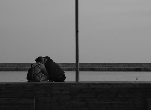 Free A black and white photo of a couple embracing by the waterfront in Kavala, Greece. Stock Photo
