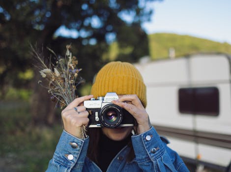 Young woman using vintage camera outdoors, close-up on nature background.
