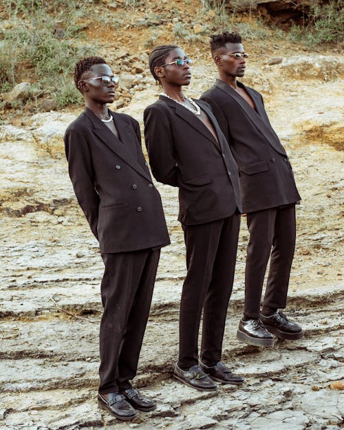 Three Men in Black Suits Standing in Row and Leaning Back