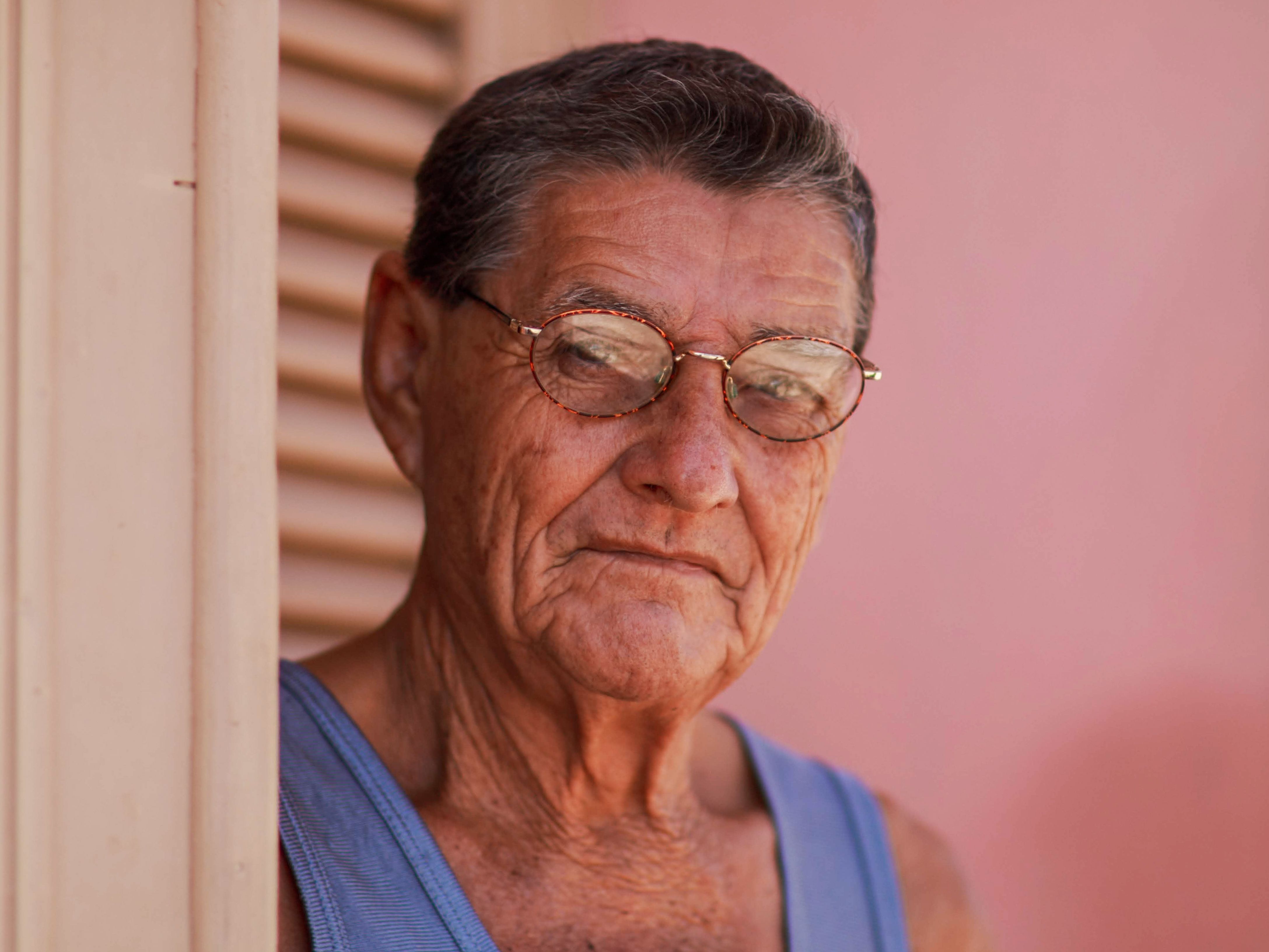 Close-up of a senior man wearing eyeglasses, captured indoors with a thoughtful expression.