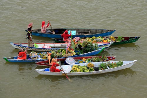 Photo of People on Boats with Fruits