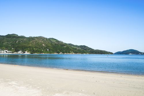 Free Tranquil beach scene on Lamma Island, Hong Kong with clear blue skies and lush greenery. Stock Photo