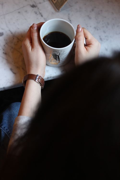 Free Hands holding a coffee mug on a marble surface in a cozy, indoor setting. Stock Photo