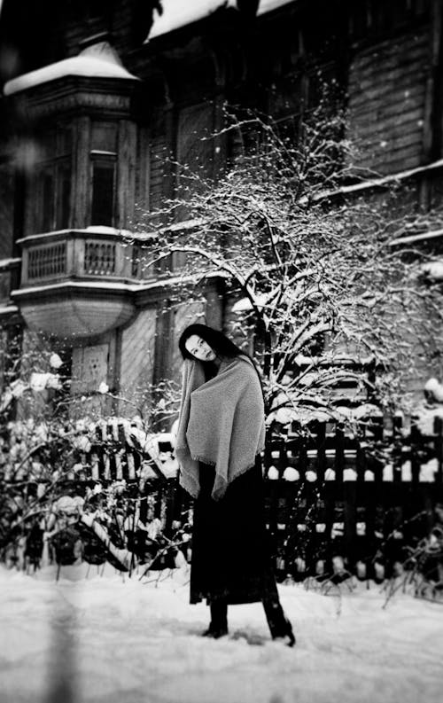 Free 겨울에 오래된 집 근처에 목도리를 두른 긴 머리를 한 소녀. 흑백 사진 Stock Photo