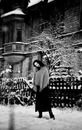 A girl with long hair in a shawl near an old house in winter. Black and white photo