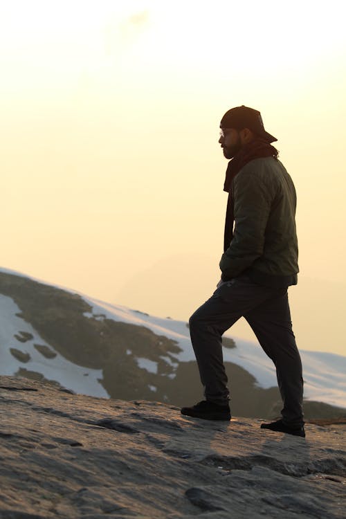 Man in Black Jacket Standing on Mountains during Sunset