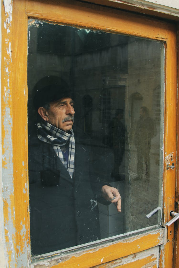 Senior Man In Warm Clothes Standing Behind Door