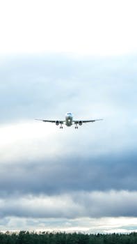 Airplane approaches landing amidst cloudy skies at Billund Airport, Denmark.