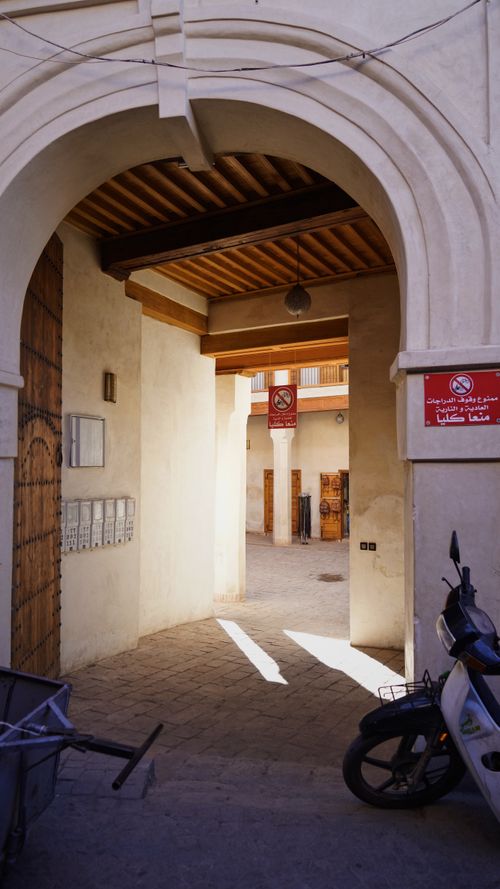 Free A traditional archway leading into a Middle Eastern marketplace, featuring a scooter and vibrant architectural details. Stock Photo