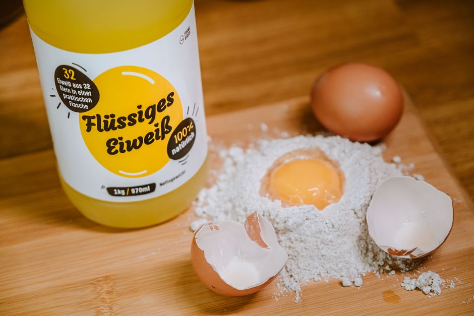 Liquid egg product with flour and eggs on a cutting board for cooking preparation.