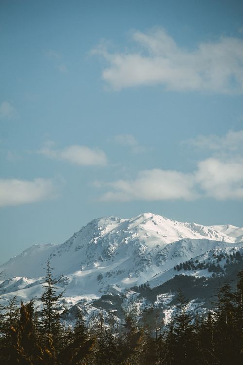 Free A picturesque snow-capped mountain range captured under a clear blue sky, epitomizing winter's beauty. Stock Photo