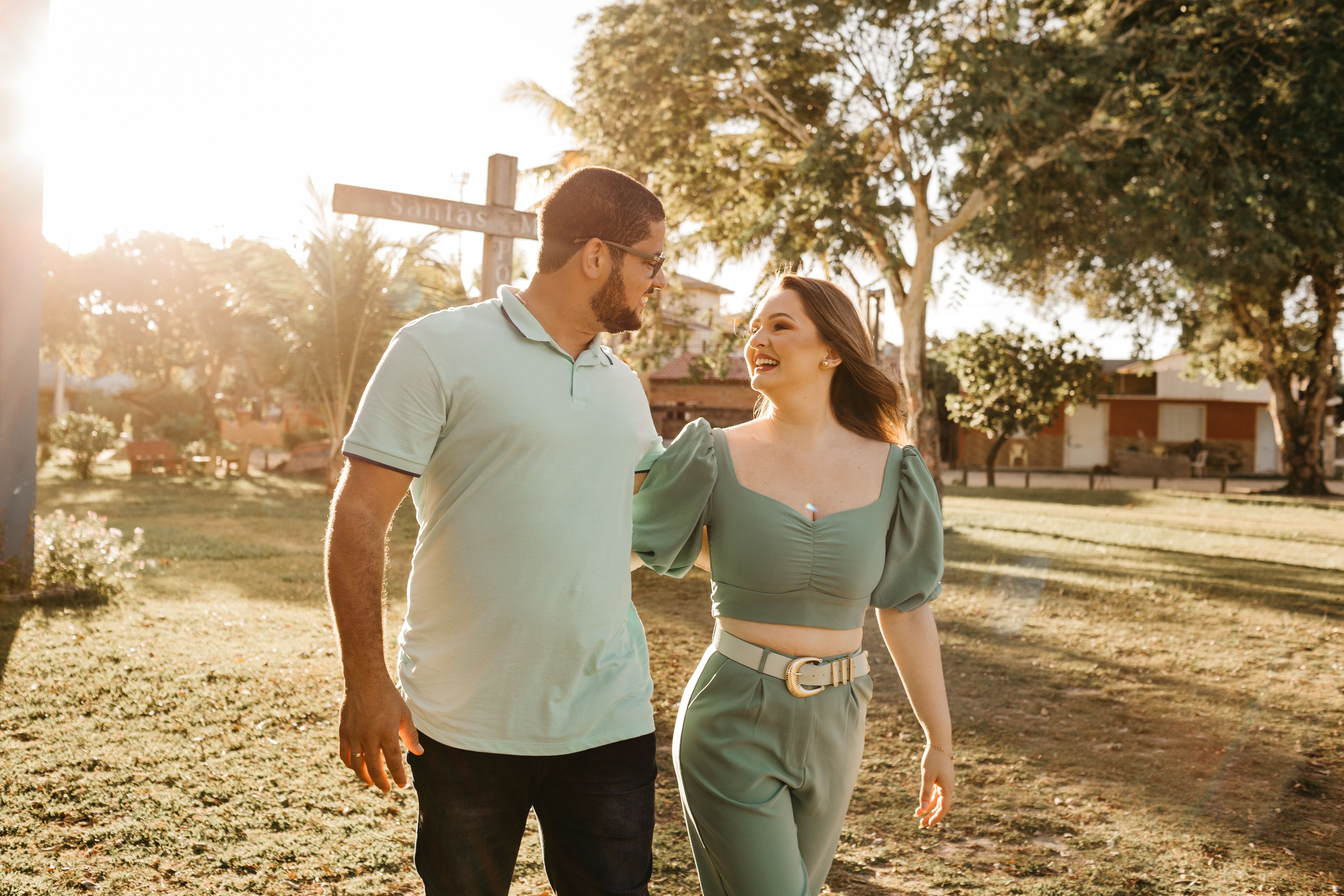 Smiling couple strolling through a sunlit park, enjoying a pleasant day together.