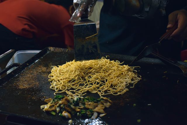 Freshly cooked noodles with vegetables on a street food grill in Jawa Timur, Indonesia.