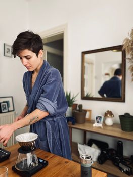 Woman in robe preparing morning coffee at home in Balıkesir, Turkey.