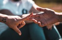 A detailed close-up of hands meeting with a small lizard on a finger, signifying connection with nature.