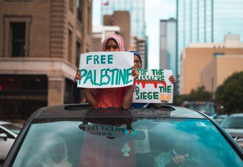 Free Two individuals holding 'Free Palestine' signs during a peaceful protest in a city center. Stock Photo