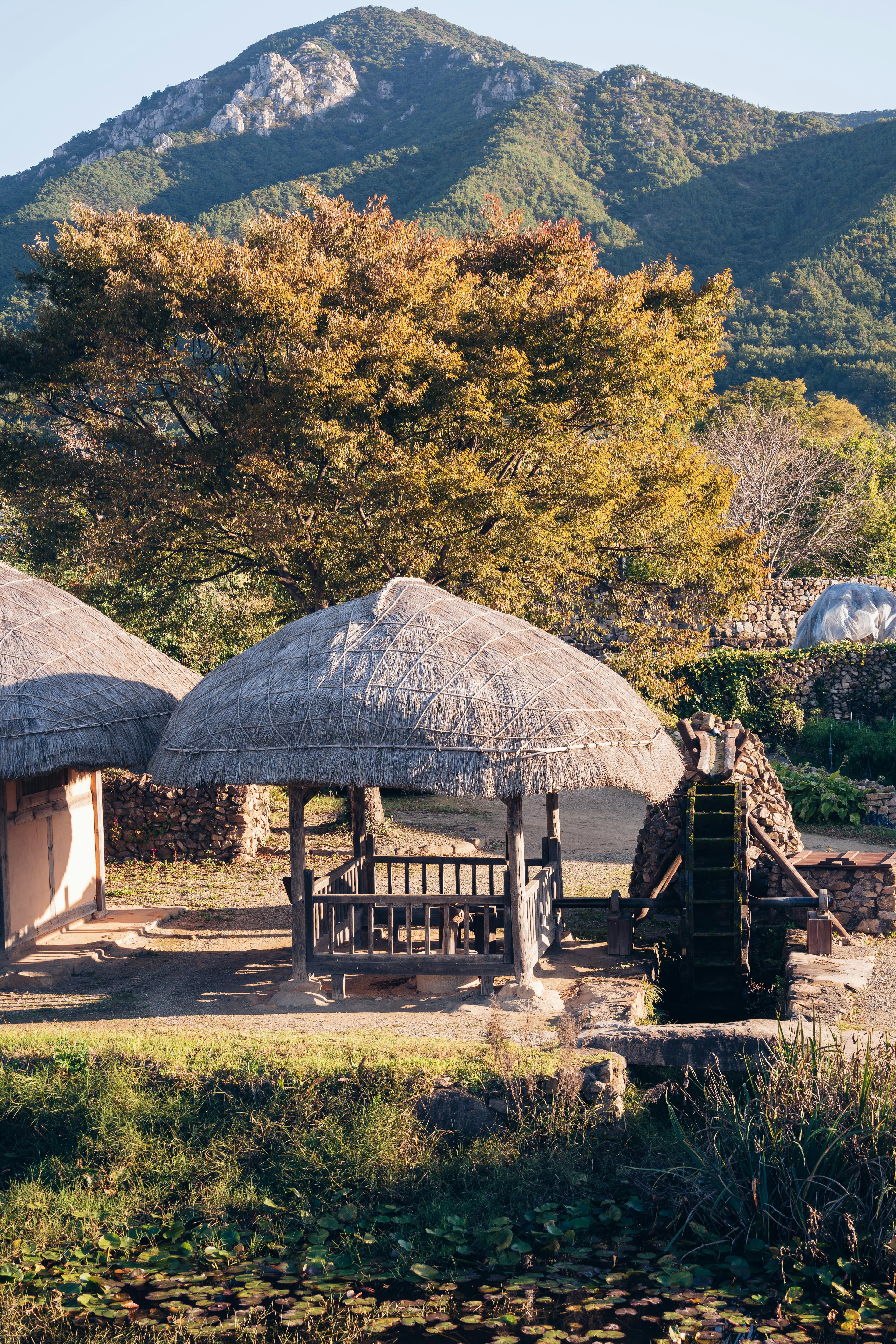 산을 배경으로 한 전통 한국 마을의 초가집 국내여행 지원금 활용 장면