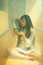 Young Girl with Long Black Hair Looking in Mirror