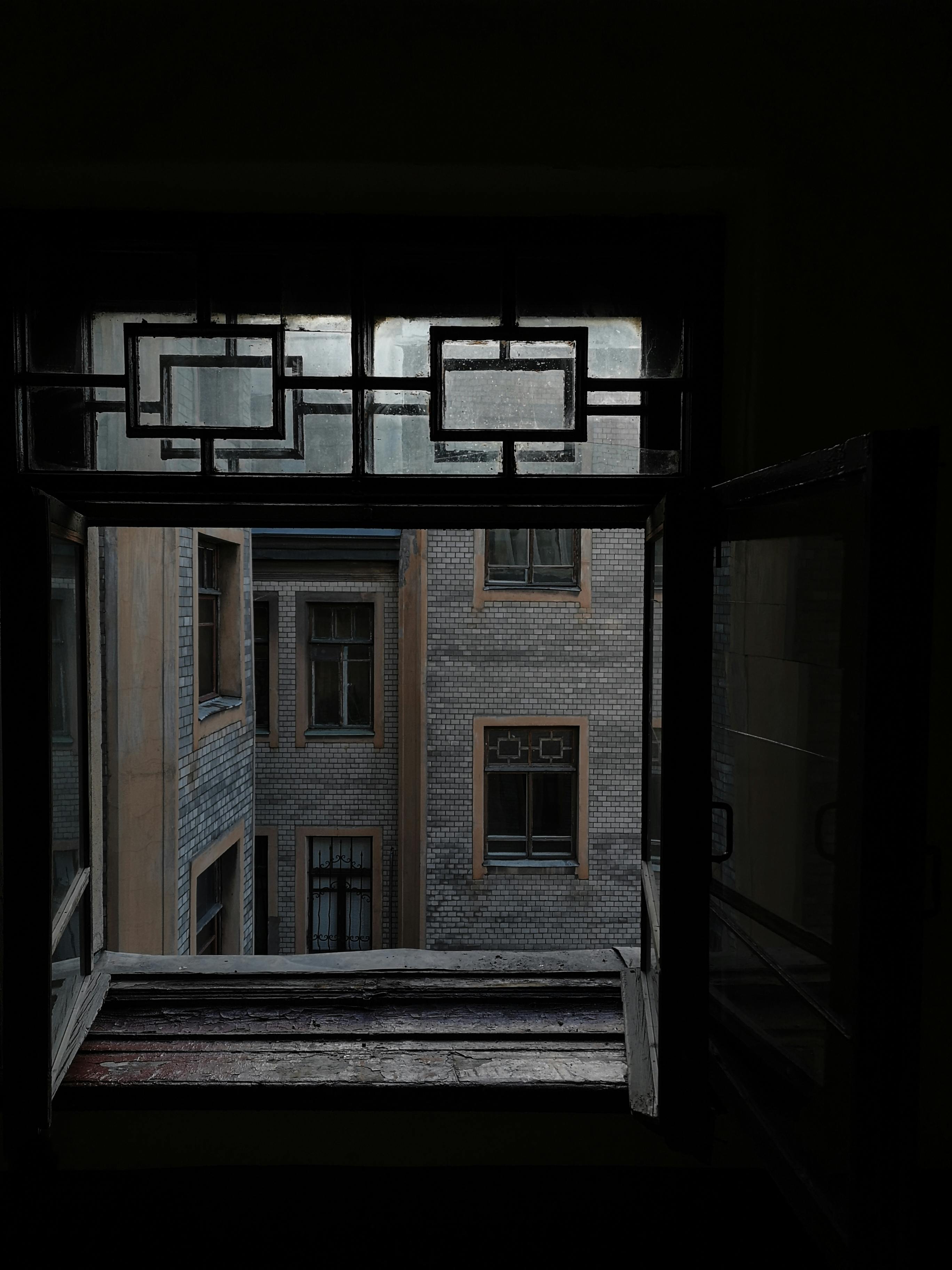 A moody exploration of urban architecture through an open window, showcasing vintage building details.