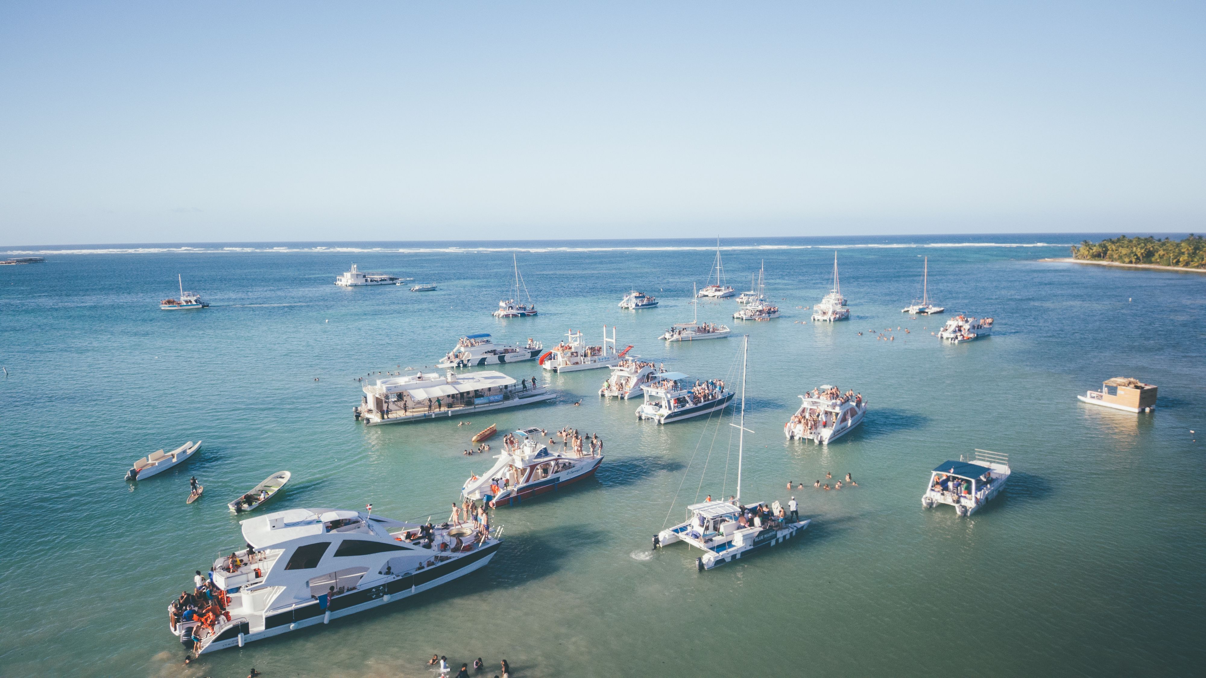 Scenic aerial view of numerous boats anchored in clear tropical waters during a sunny day.