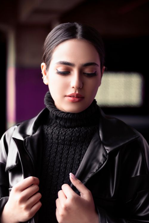 Free Elegant portrait of a woman wearing a black leather jacket and turtleneck indoors. Stock Photo