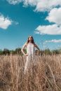 Woman in White Sleeveless Dress Standing on Brown Grass Field Under Blue Sky
