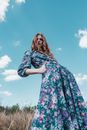 Woman in White Pink and Blue Floral Long Sleeve Dress Standing on Green Grass Field during