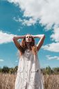 Woman in White Sleeveless Dress Standing on Green Grass Field Under Blue Sky