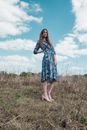 Woman in Blue and White Floral Dress Standing on Green Grass Field