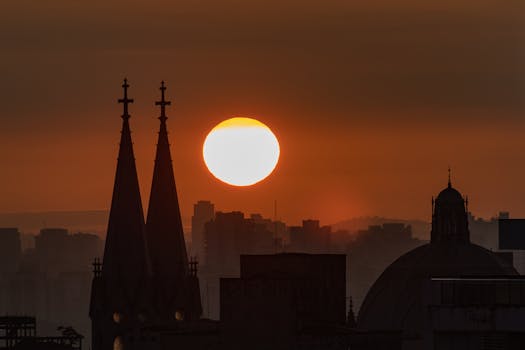 Beautiful sunrise casting silhouettes over city skyline with architectural spires in view.