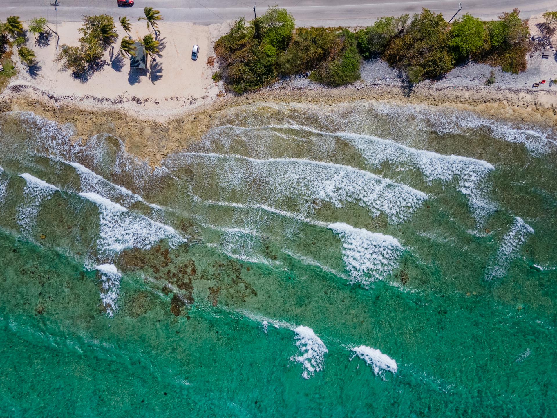 Stunning aerial view of a tropical beach with crystal clear waters and gentle waves in the Cayman Islands.