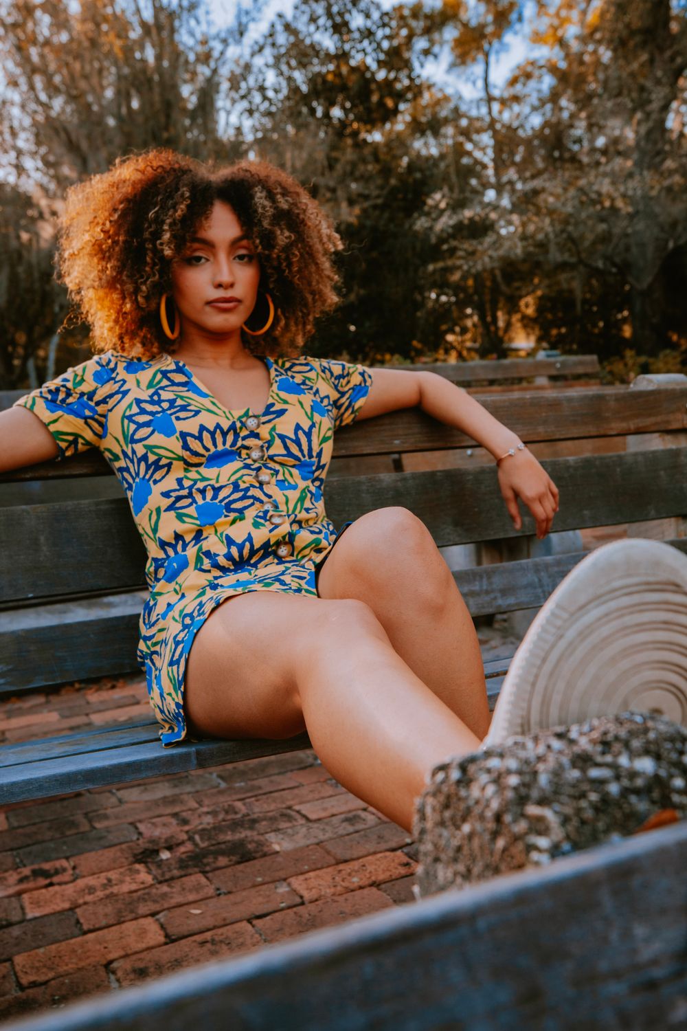 A Woman in Blue and Yellow Floral Dress Sitting on Brown Wooden Bench ...