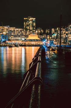Illuminated North Vancouver waterfront with city lights reflecting in the harbor at night.
