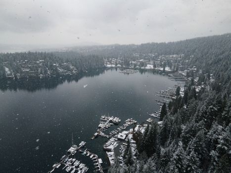 Aerial view of a snow-covered lake in British Columbia, amidst a serene winter landscape.