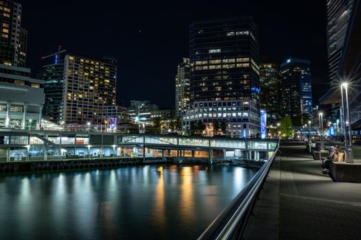 Stunning night cityscape of Vancouver with illuminated skyscrapers reflecting in the water.