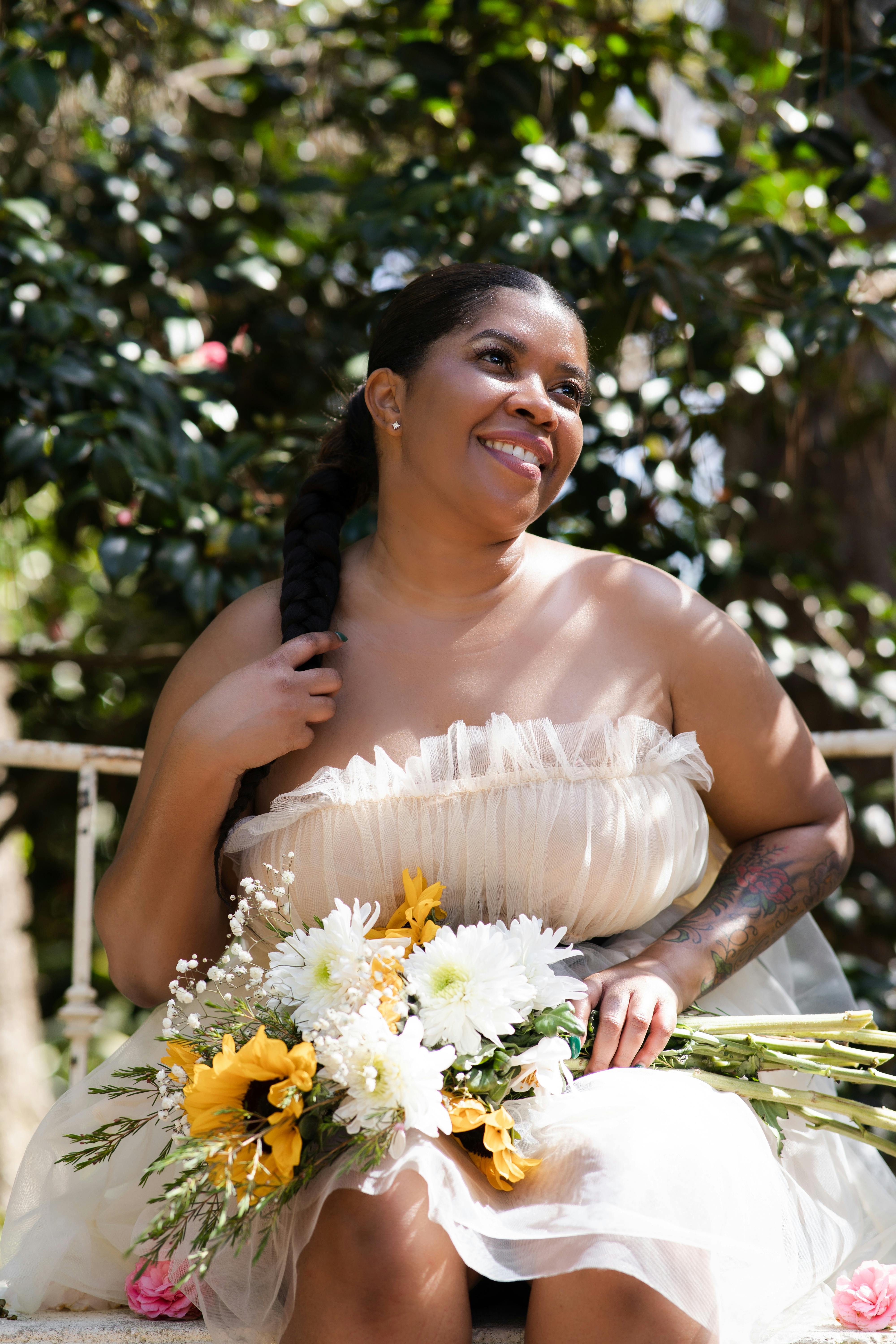 Woman in White Dress Holding White and Yellow Flowers Free Stock