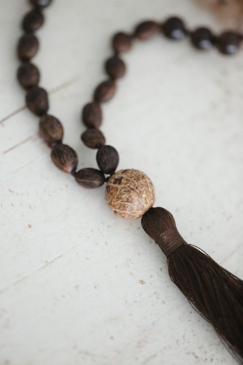 Free A detailed photograph of wooden prayer beads with a tassel against a light background. Stock Photo