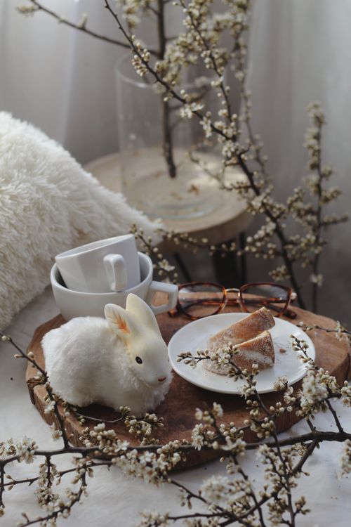 Free Easter-themed tabletop with rabbit decoration, coffee cups, and cake slices for a cozy spring vibe. Stock Photo
