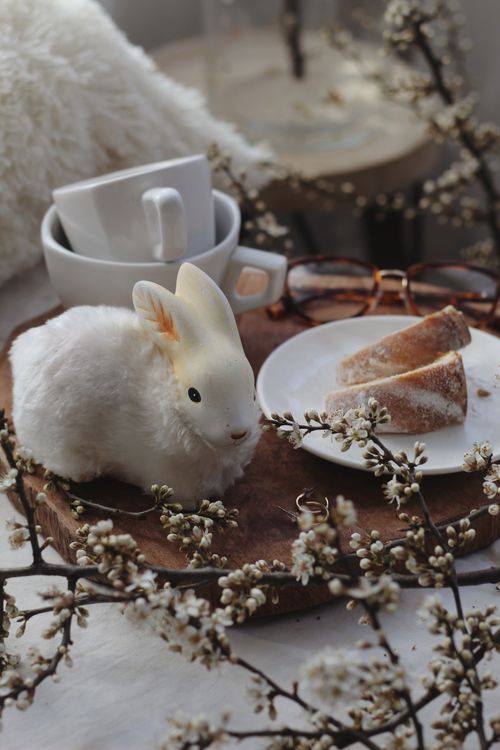 Free A charming Easter arrangement with rabbit decor, dessert, and blossoms. Stock Photo