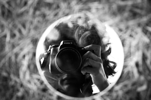 Free Grayscale Photo of Person Holding a Camera Stock Photo