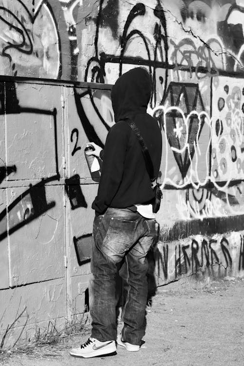 A Person Wearing Black Hoodie Vandalizing the Wall