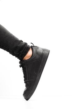 Close-up of a black sneaker in motion against a crisp white background.