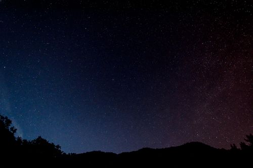 Free A serene view of a star-filled night sky over silhouettes of hills in Italy. Stock Photo
