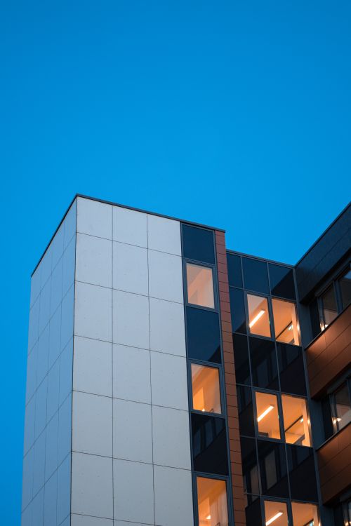 Free Low angle view of a modern high-rise with glass panels against clear sky. Stock Photo