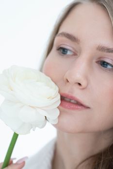 Close-up portrait of a woman gently holding a white rose, capturing elegance and softness.