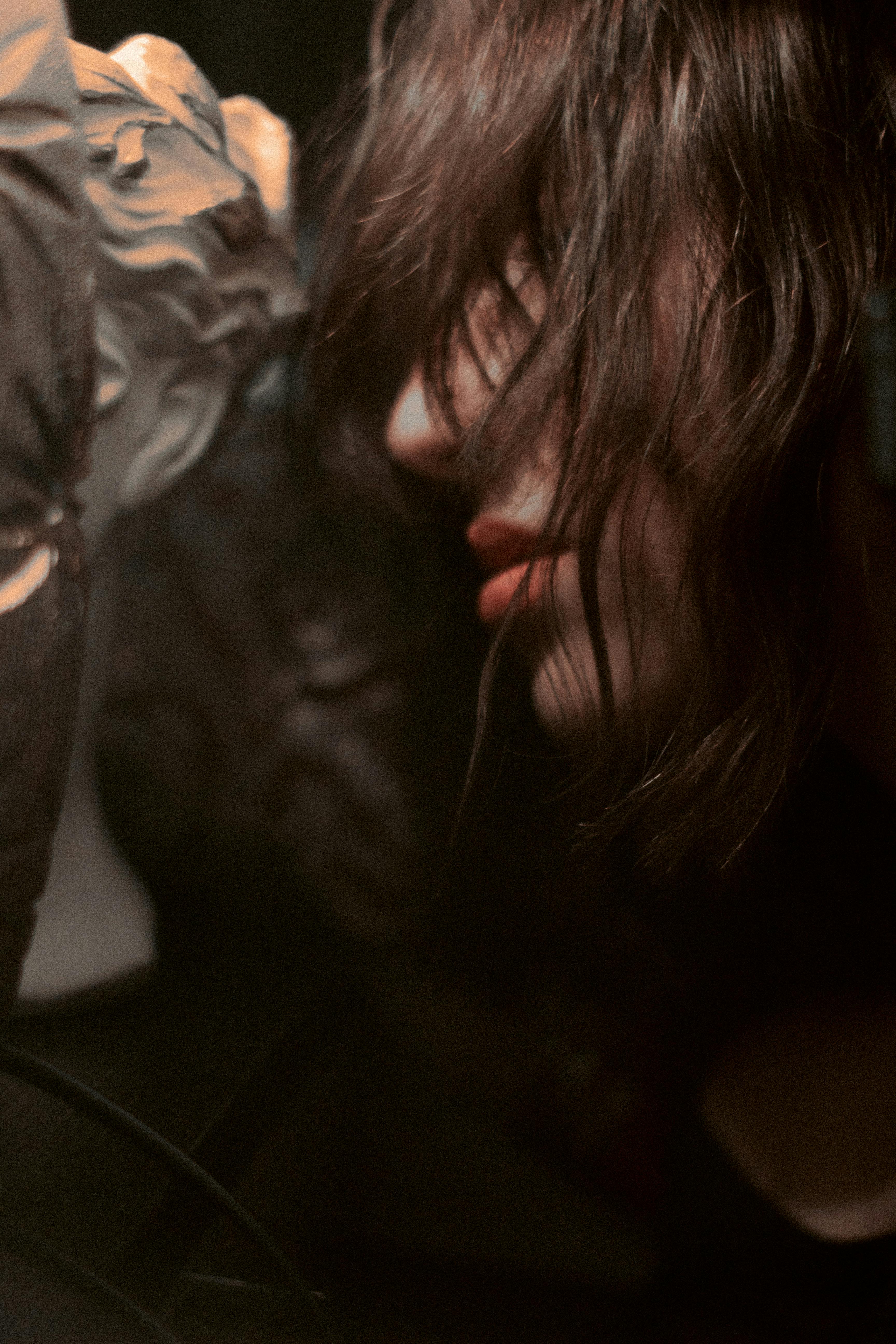 Close-up artistic portrait of a woman half-shrouded in shadow, creating a mysterious and dramatic mood.