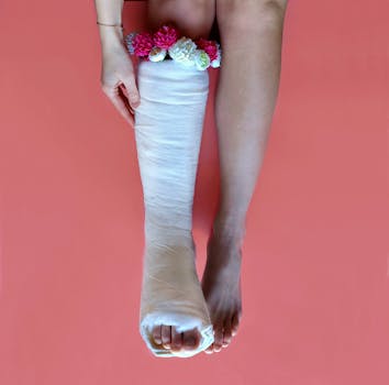 A leg with a cast adorned with colorful flowers on a pink background, blending beauty and recovery.